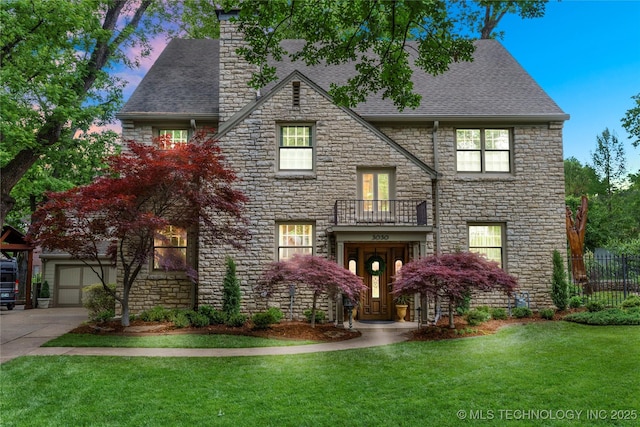 view of front of house with a garage, a balcony, and a yard