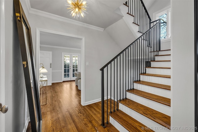 foyer entrance featuring ornamental molding, dark wood-type flooring, a chandelier, and french doors