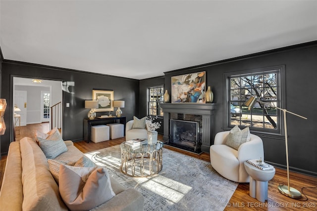 living room with plenty of natural light, a fireplace, wood finished floors, and stairs