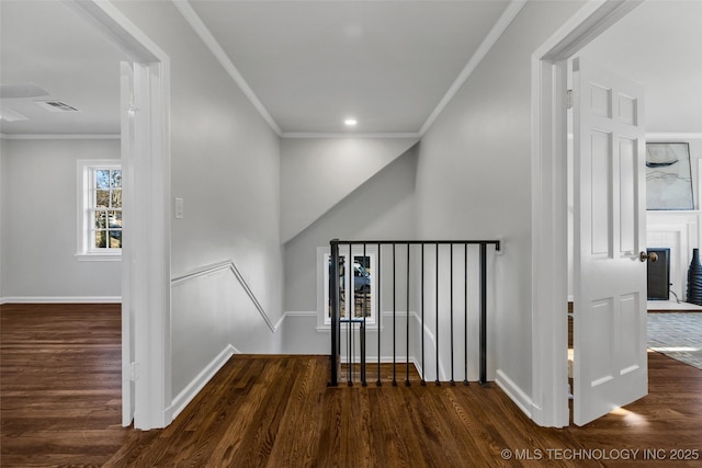 hall featuring wood finished floors, visible vents, baseboards, an upstairs landing, and crown molding