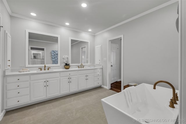 bathroom with a freestanding bath, double vanity, a sink, and recessed lighting