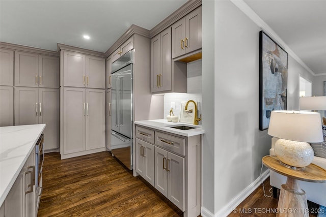 kitchen featuring stainless steel built in fridge, a sink, dark wood finished floors, and gray cabinetry