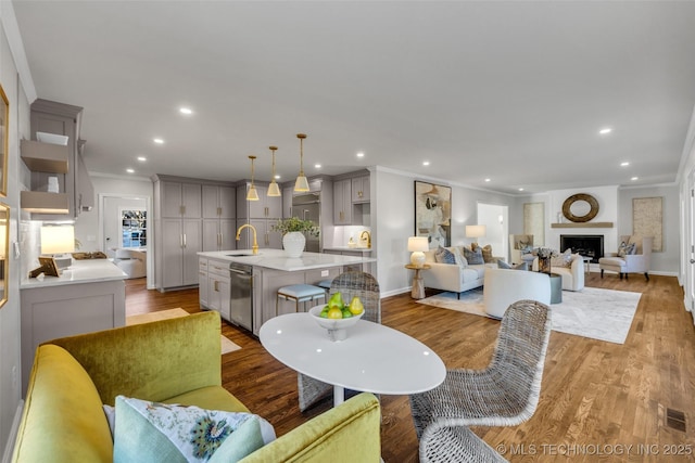 living area featuring a fireplace, crown molding, recessed lighting, visible vents, and wood finished floors