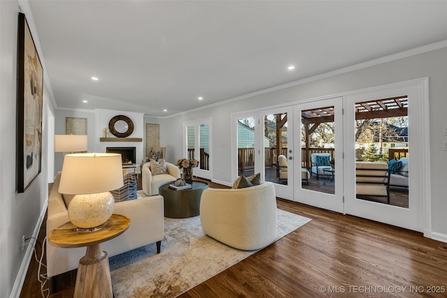 living area featuring french doors, a fireplace, recessed lighting, ornamental molding, and wood finished floors