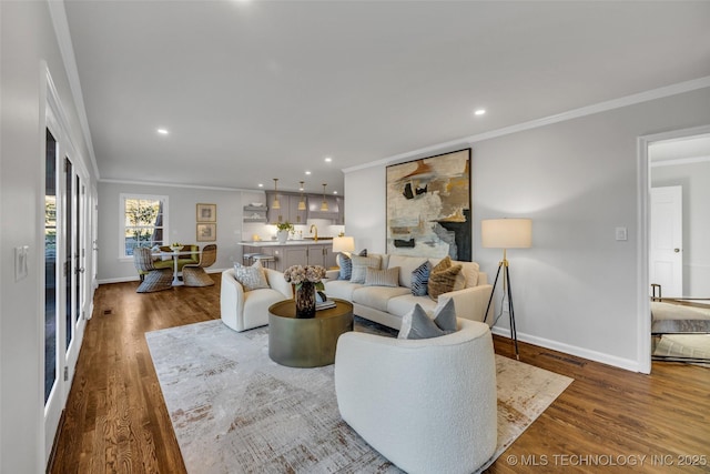 living area with ornamental molding, wood finished floors, and baseboards