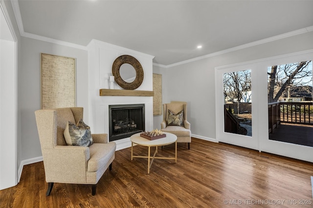 living area with a fireplace, crown molding, baseboards, and wood finished floors