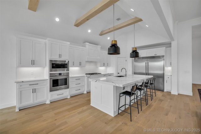 kitchen with pendant lighting, white cabinetry, an island with sink, sink, and built in appliances