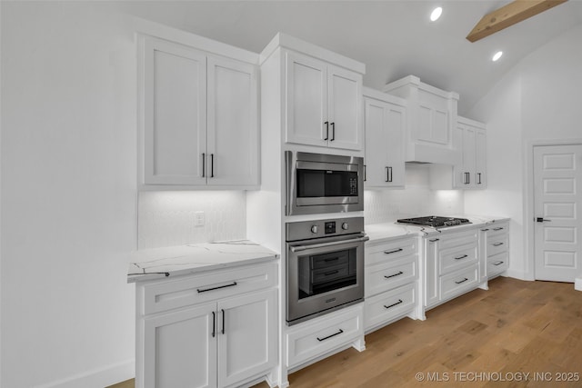 kitchen featuring white cabinetry, appliances with stainless steel finishes, lofted ceiling, and light hardwood / wood-style flooring