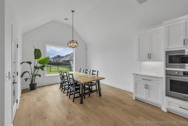 dining area with lofted ceiling, light hardwood / wood-style flooring, and a chandelier