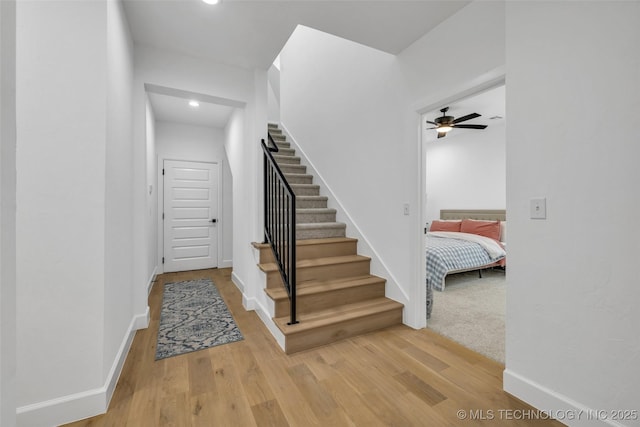 staircase featuring wood-type flooring and ceiling fan