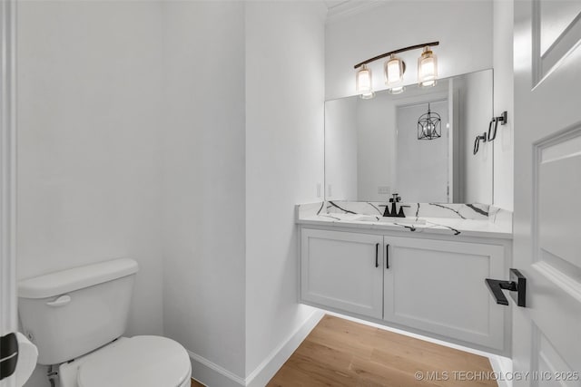 bathroom featuring hardwood / wood-style flooring, vanity, crown molding, and toilet