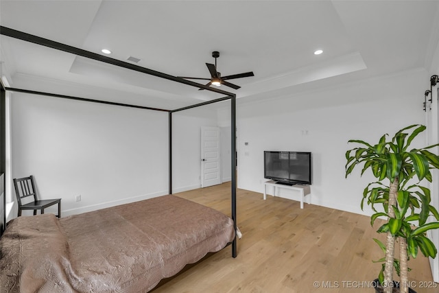 bedroom featuring crown molding, a tray ceiling, ceiling fan, and light hardwood / wood-style flooring