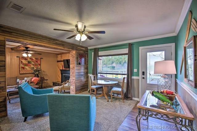 living room featuring crown molding, ceiling fan, hardwood / wood-style floors, and a textured ceiling