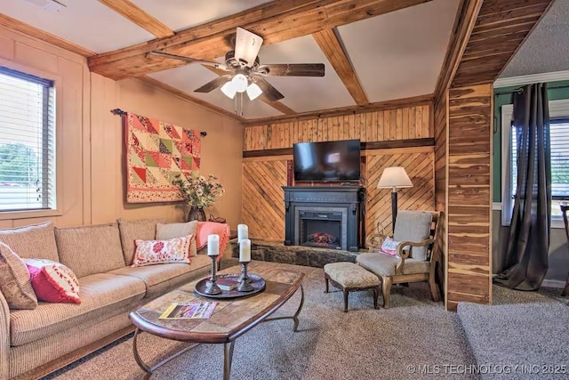 living room with ceiling fan, ornamental molding, beamed ceiling, and wood walls