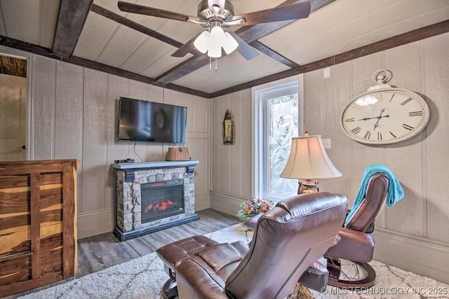 living room with a fireplace, beam ceiling, wood-type flooring, and ceiling fan