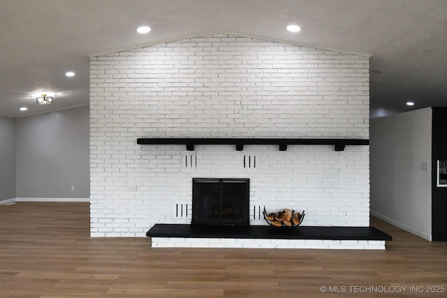 unfurnished living room with lofted ceiling, a brick fireplace, and hardwood / wood-style flooring