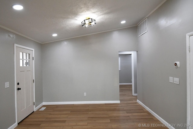 entryway with hardwood / wood-style flooring, crown molding, and a textured ceiling