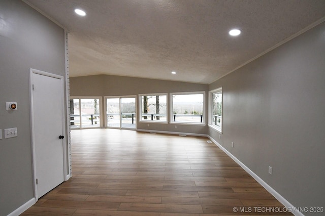 empty room featuring hardwood / wood-style flooring, vaulted ceiling, and a healthy amount of sunlight