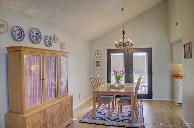 dining space featuring french doors, vaulted ceiling, a textured ceiling, a notable chandelier, and light hardwood / wood-style floors