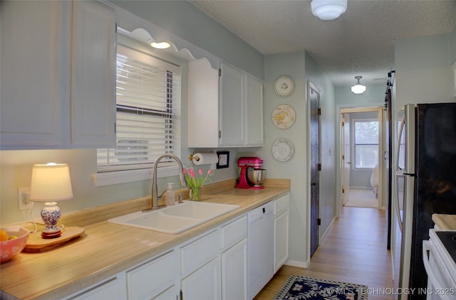 kitchen featuring range with electric stovetop, stainless steel refrigerator, white cabinetry, sink, and white dishwasher