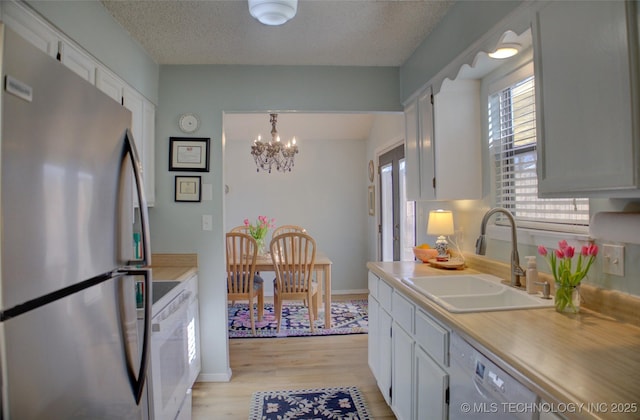 kitchen featuring pendant lighting, sink, white appliances, and white cabinets