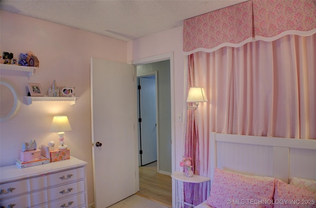 bedroom with light hardwood / wood-style flooring and a textured ceiling