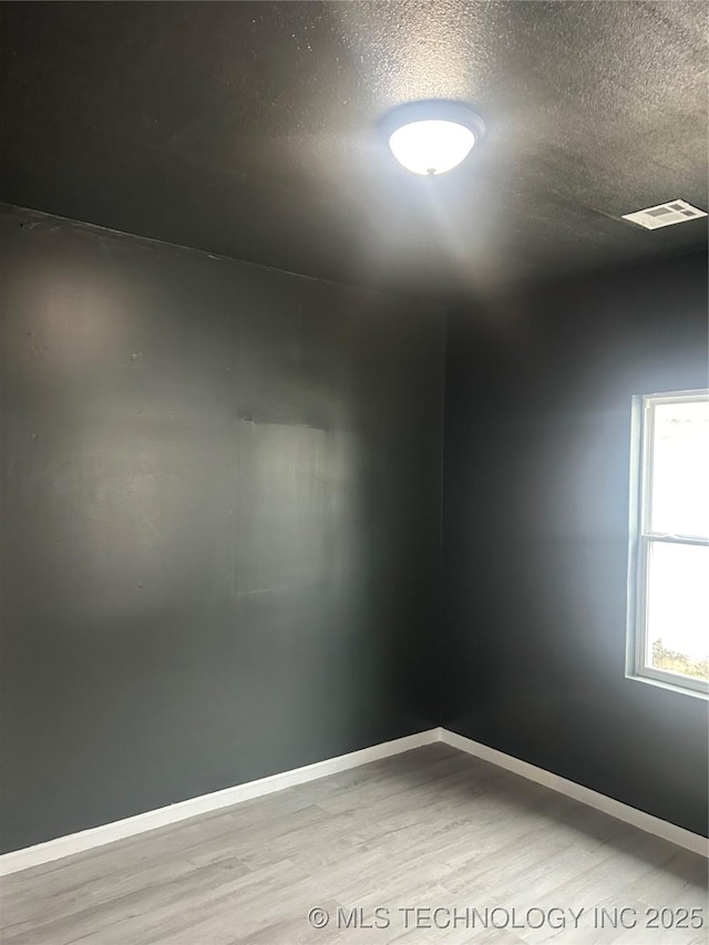 unfurnished room with wood-type flooring and a textured ceiling