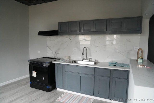 kitchen featuring tasteful backsplash, gray cabinetry, sink, and light wood-type flooring