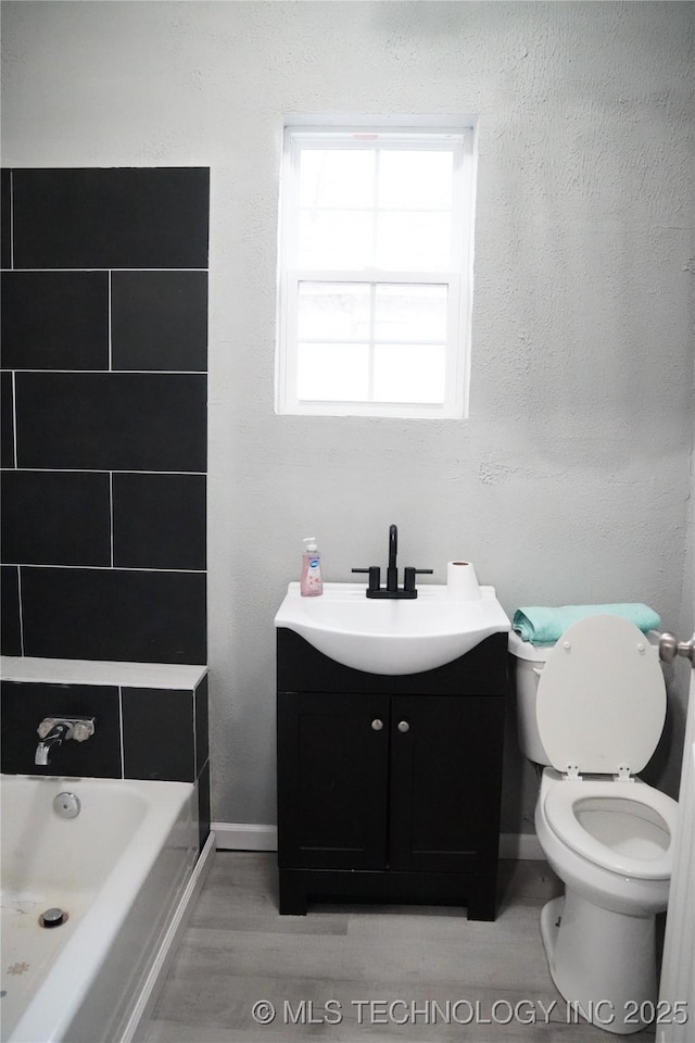 bathroom featuring toilet, vanity, and a bath