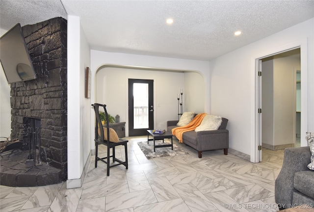 living area with a fireplace and a textured ceiling