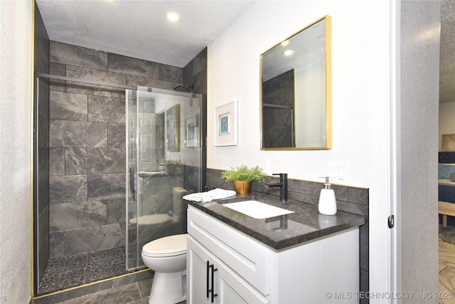 bathroom featuring vanity, a textured ceiling, a shower with shower door, and toilet