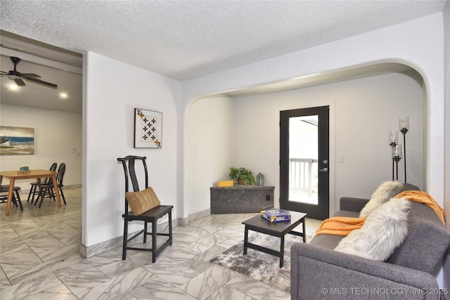 living room with ceiling fan and a textured ceiling