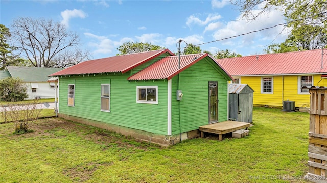 rear view of house with cooling unit and a yard