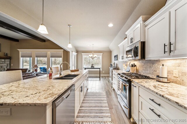 kitchen with pendant lighting, an island with sink, stainless steel appliances, and sink