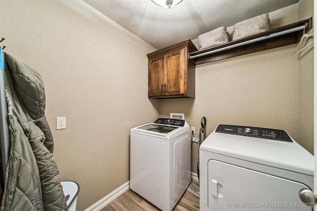 washroom featuring cabinets, light wood-type flooring, and independent washer and dryer