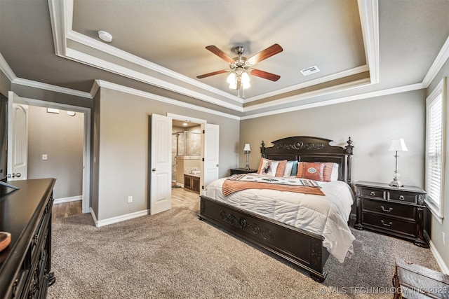 bedroom featuring connected bathroom, ornamental molding, a raised ceiling, carpet floors, and ceiling fan