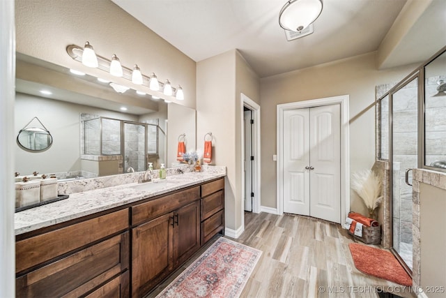 bathroom featuring vanity, a shower with shower door, and wood-type flooring