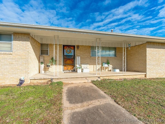 view of exterior entry featuring a yard and covered porch