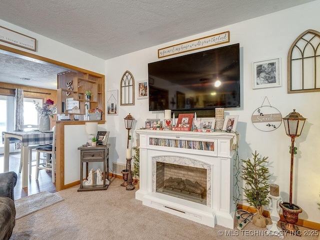 carpeted living room featuring a high end fireplace and a textured ceiling