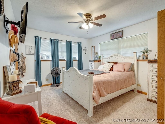 carpeted bedroom featuring ceiling fan and a textured ceiling