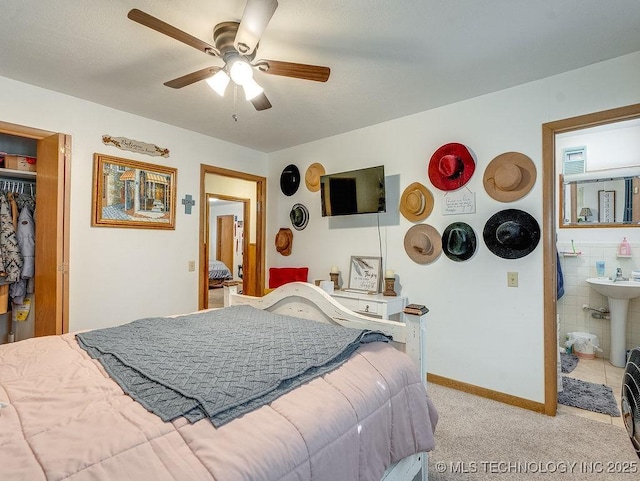 carpeted bedroom with ensuite bathroom, sink, and ceiling fan