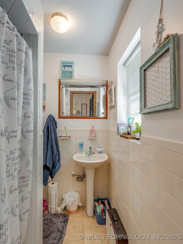 bathroom with tile walls, sink, curtained shower, and tile patterned floors