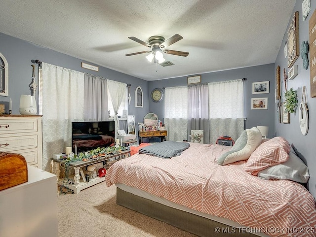 bedroom with ceiling fan, carpet floors, and a textured ceiling