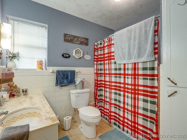 bathroom featuring tile walls, vanity, a textured ceiling, tile patterned floors, and toilet