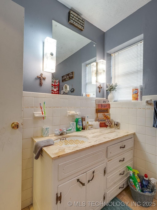 bathroom with tile walls, vanity, tile patterned flooring, and a textured ceiling