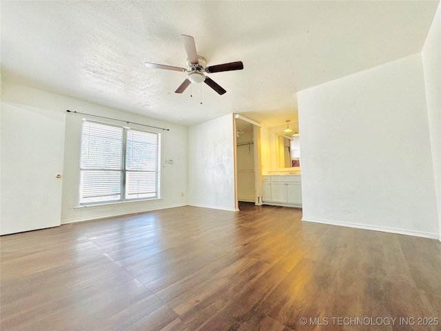 unfurnished living room featuring ceiling fan, hardwood / wood-style floors, and a textured ceiling