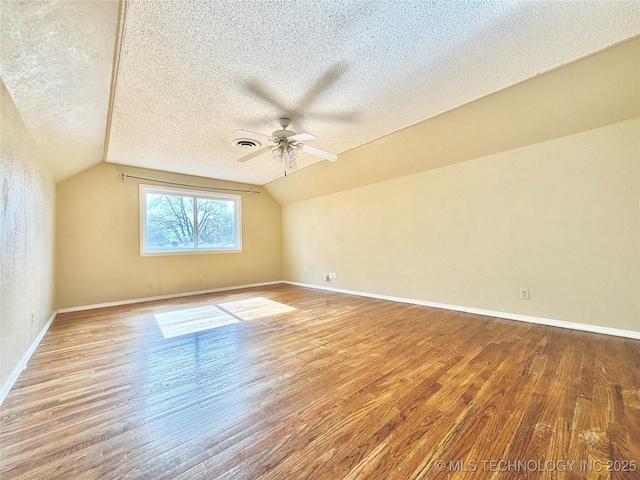 additional living space featuring ceiling fan, wood-type flooring, vaulted ceiling, and a textured ceiling