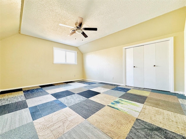 unfurnished bedroom with vaulted ceiling, ceiling fan, a textured ceiling, and a closet