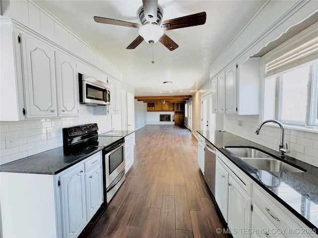 kitchen with sink, dark stone countertops, dark hardwood / wood-style flooring, stainless steel appliances, and white cabinets