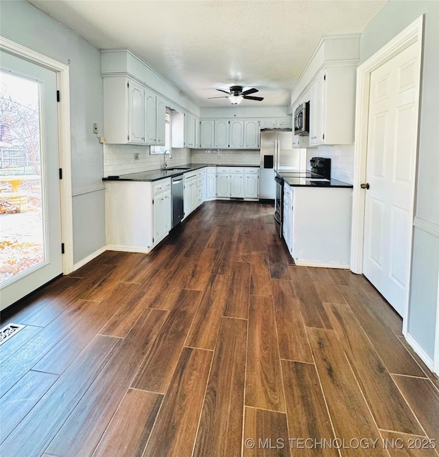 kitchen with decorative backsplash, dark wood-type flooring, white cabinets, and appliances with stainless steel finishes